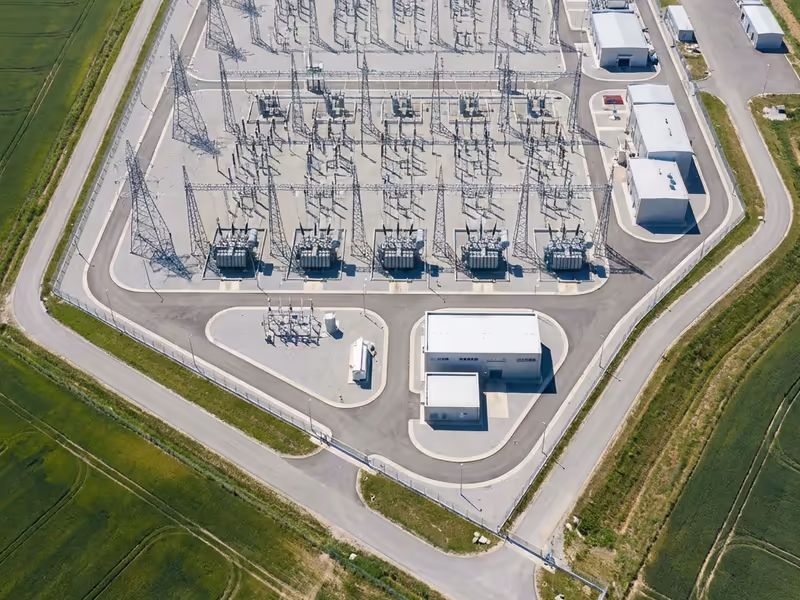 Aerial view of an electrical substation with multiple transformers and transmission towers