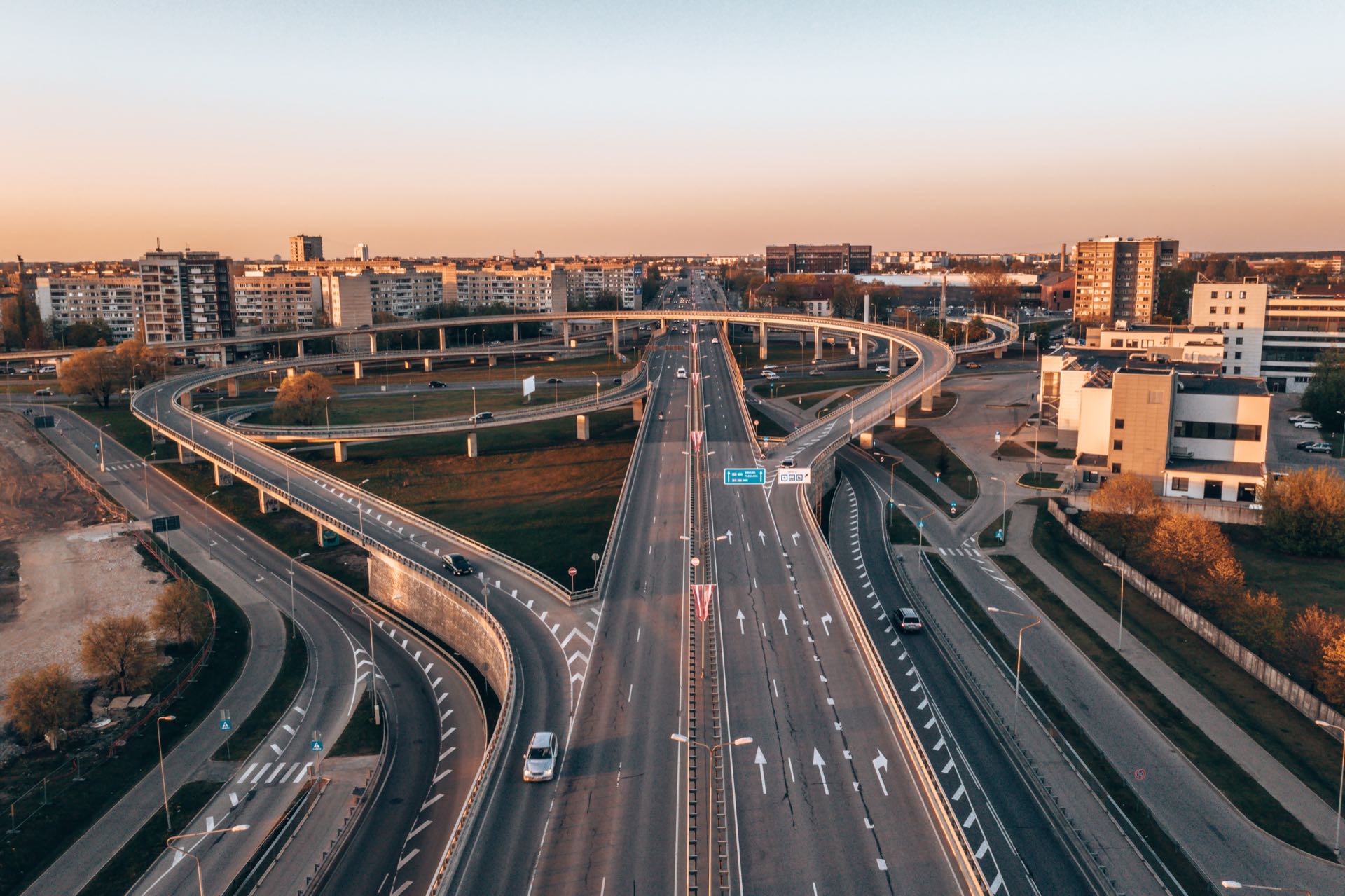 Aerial view of a multi-lane highway interchange with vehicles and surrounding green areas