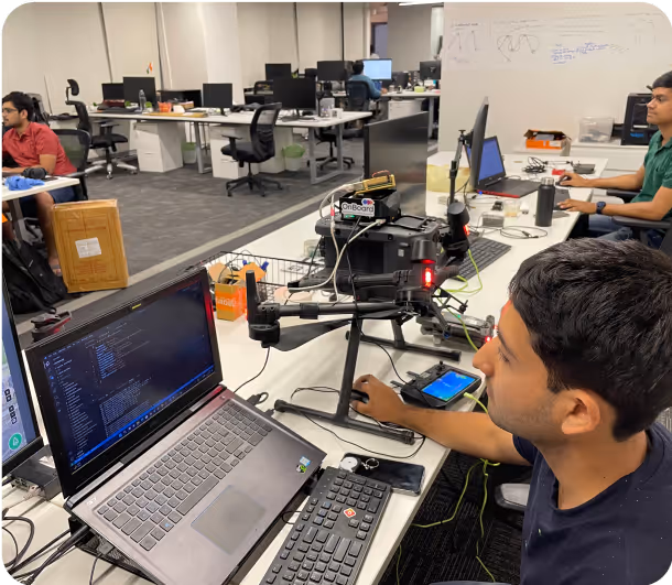 Operator controls a drone with a laptop and phone in the field.