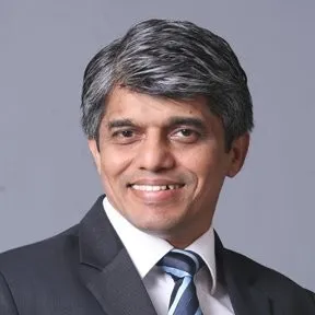 Portrait of Gireendra Kasmalkar smiling in a suit.
