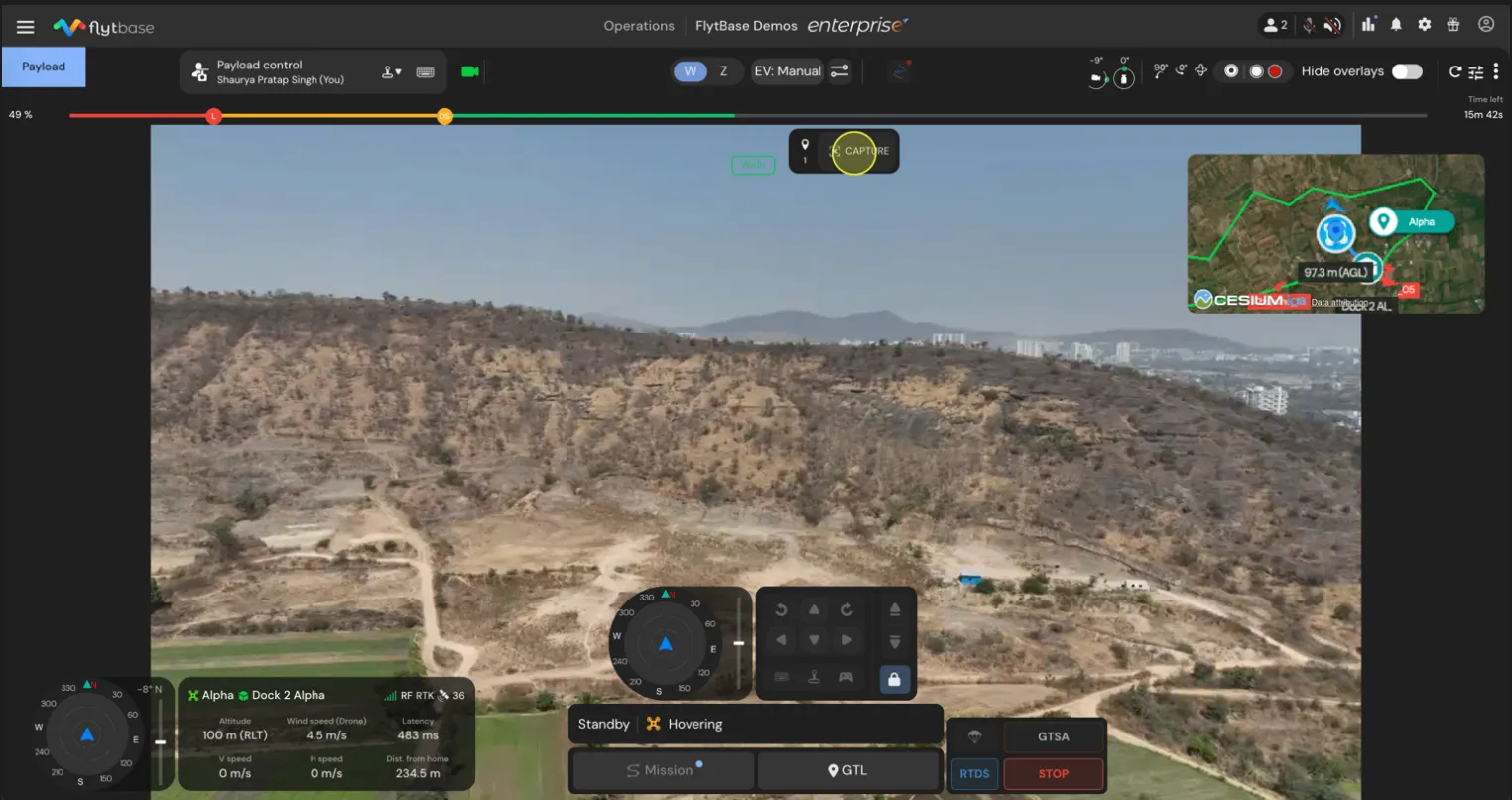 Drone flight control interface showing aerial view of a hilly landscape with telemetry overlays