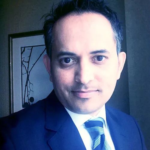 Retrato de Sanjay Kanvinde con un traje oscuro mirando a la cámara.